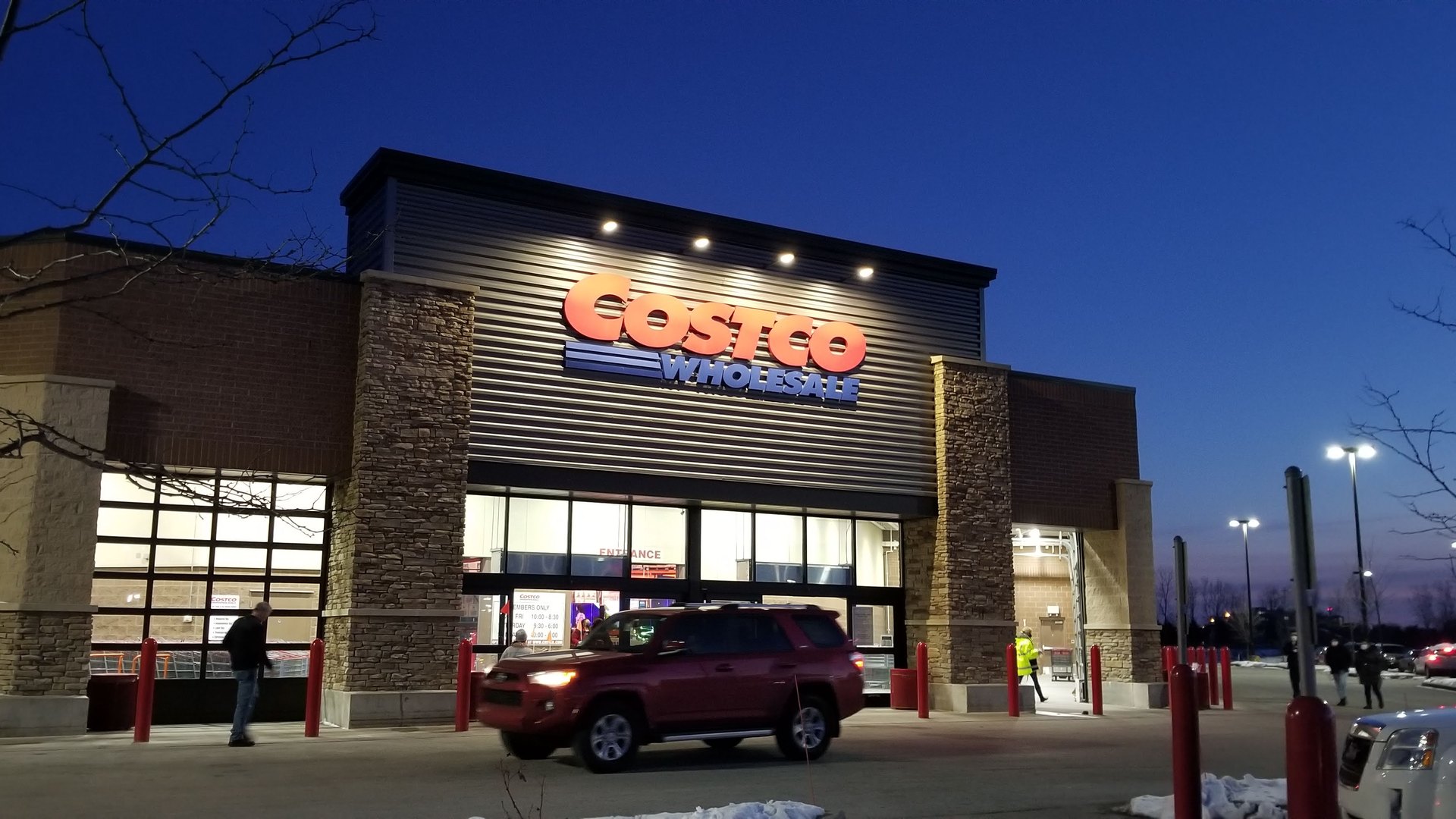 Exterior of a Costco Wholesale warehouse in the United States at dusk, with the illuminated Costco Wholesale sign above the entrance